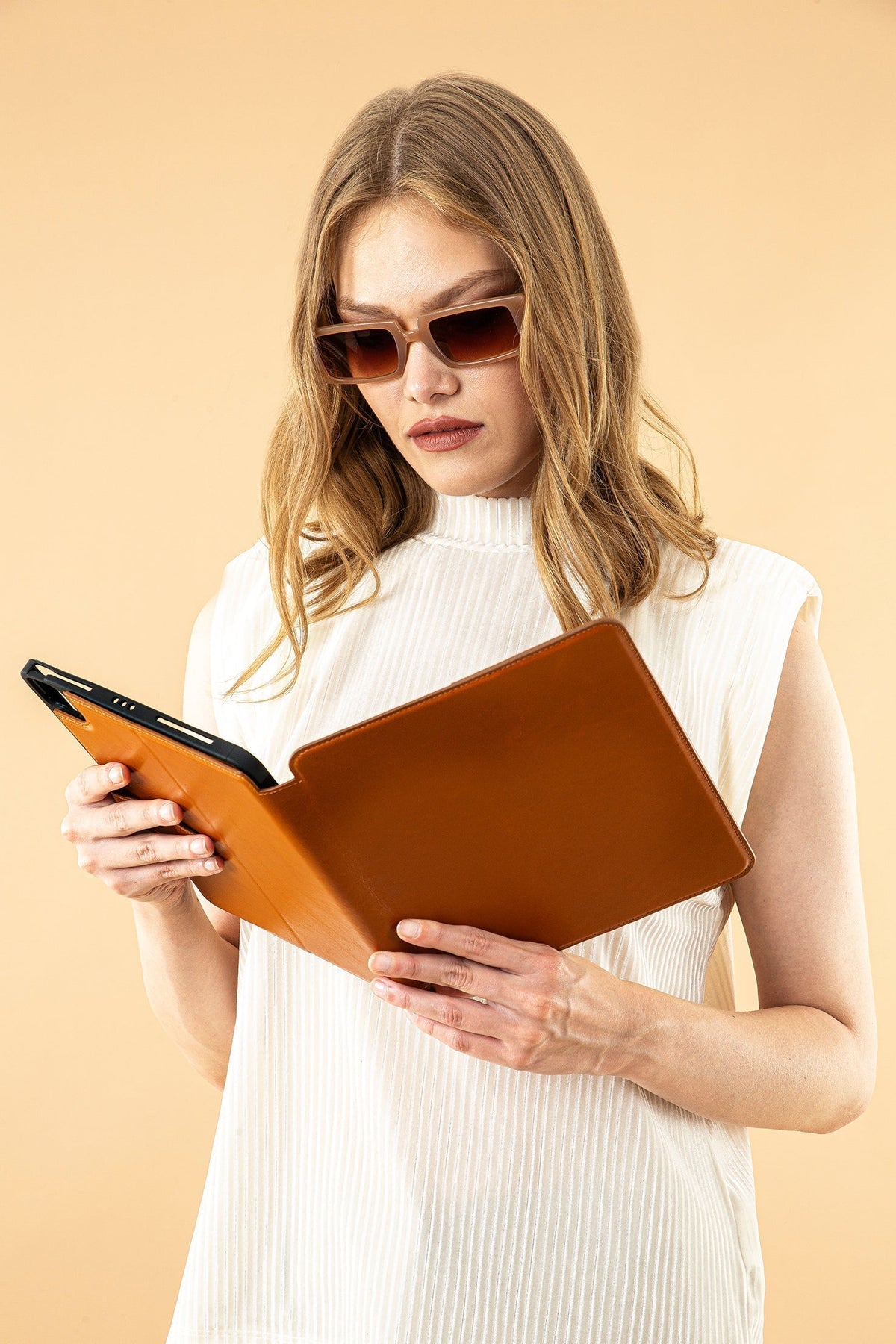 Woman holding tan leather iPad folio case while reading, front view