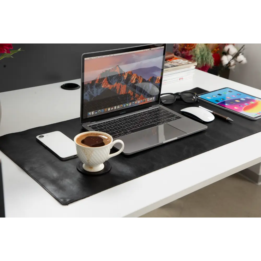 Laptop on a desk with a coffee cup, phone, and tablet