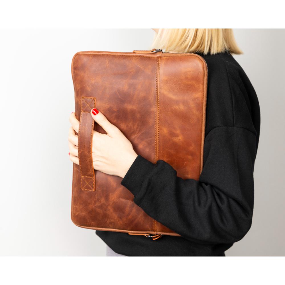 Person holding a brown leather portfolio against a plain background