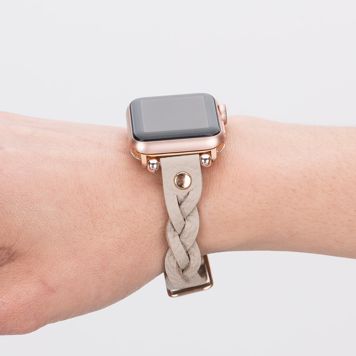 Smartwatch with a braided beige strap on a wrist against a light background