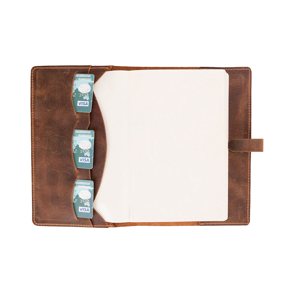 A brown leather journal cover with a wrap-around strap and three card slots, displayed with a white notebook inserted.