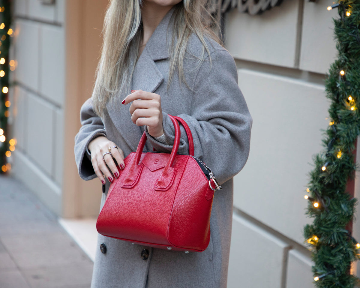 Person holding a red handbag with festive decorations in the background