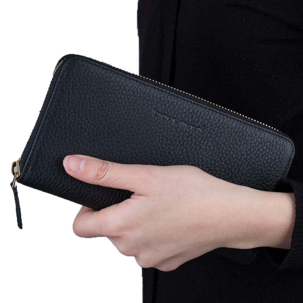 Hand holding a black wallet with a visible brand name on a white background