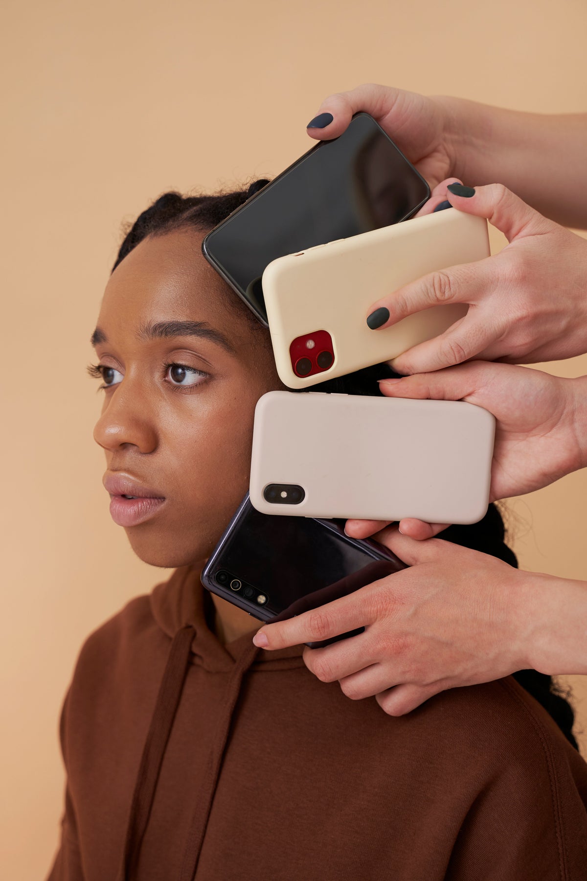 Close-up of a woman surrounded by multiple smartphones with colorful cases, representing different phone models and modern mobile technology.