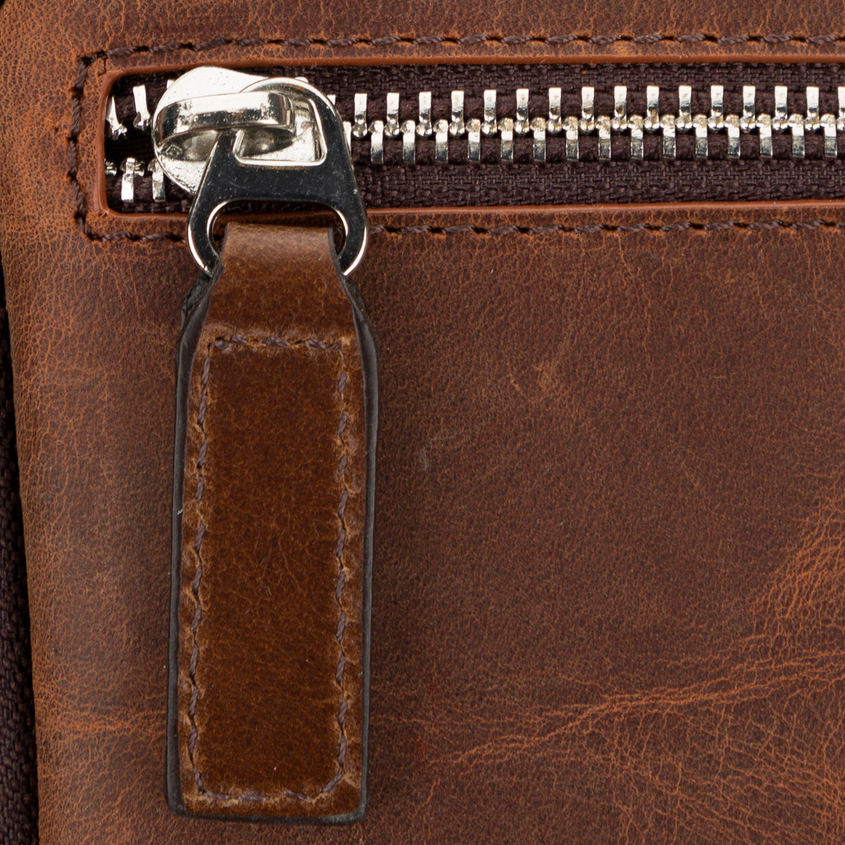 Close-up of a brown leather bag with a zipper
