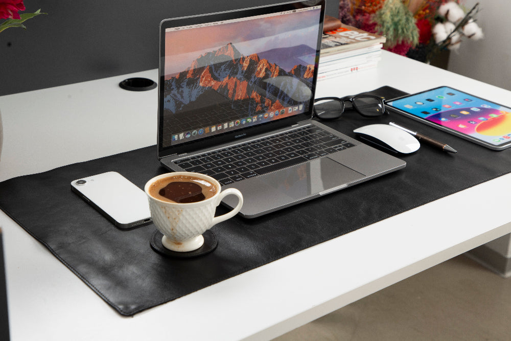 Laptop on a desk with a coffee cup, phone, and tablet