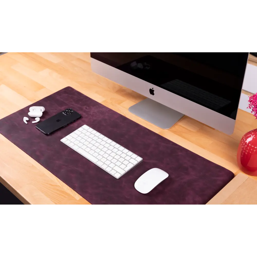 Desk setup with computer, keyboard, mouse, and phone on a purple mat.