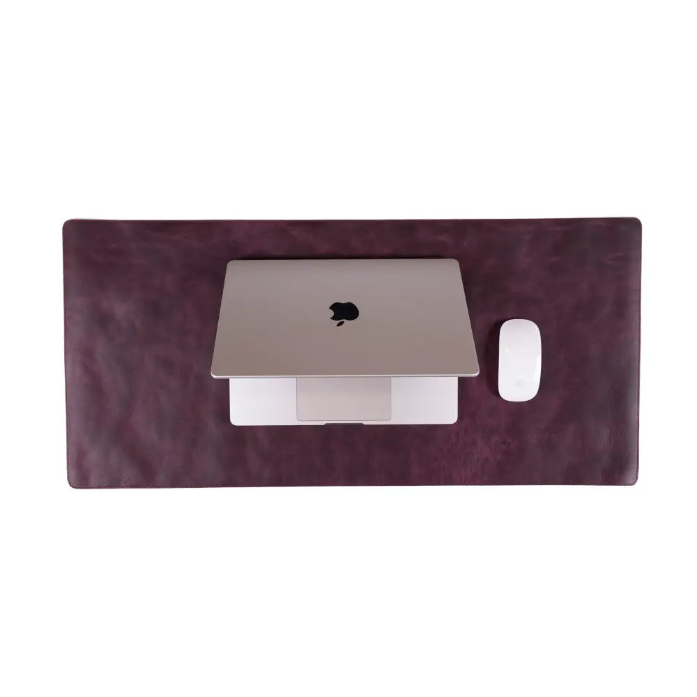 Laptop and phone on a purple desk mat with a white background