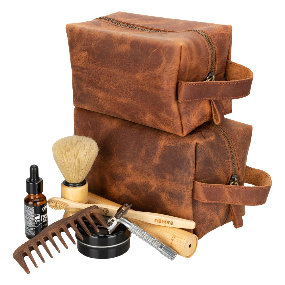 Brown leather toiletry bag with grooming tools on a white background