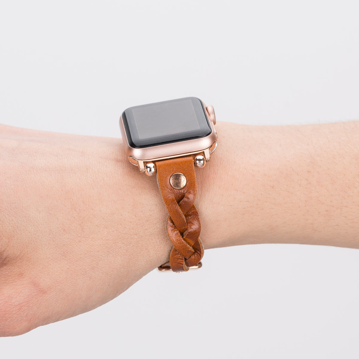 Smartwatch with a brown braided leather strap on a wrist against a light gray background