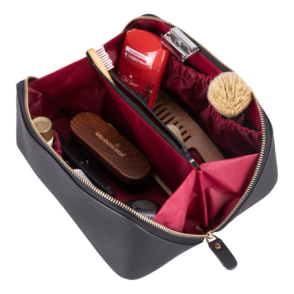 Open black leather makeup bag with grooming products on a white background