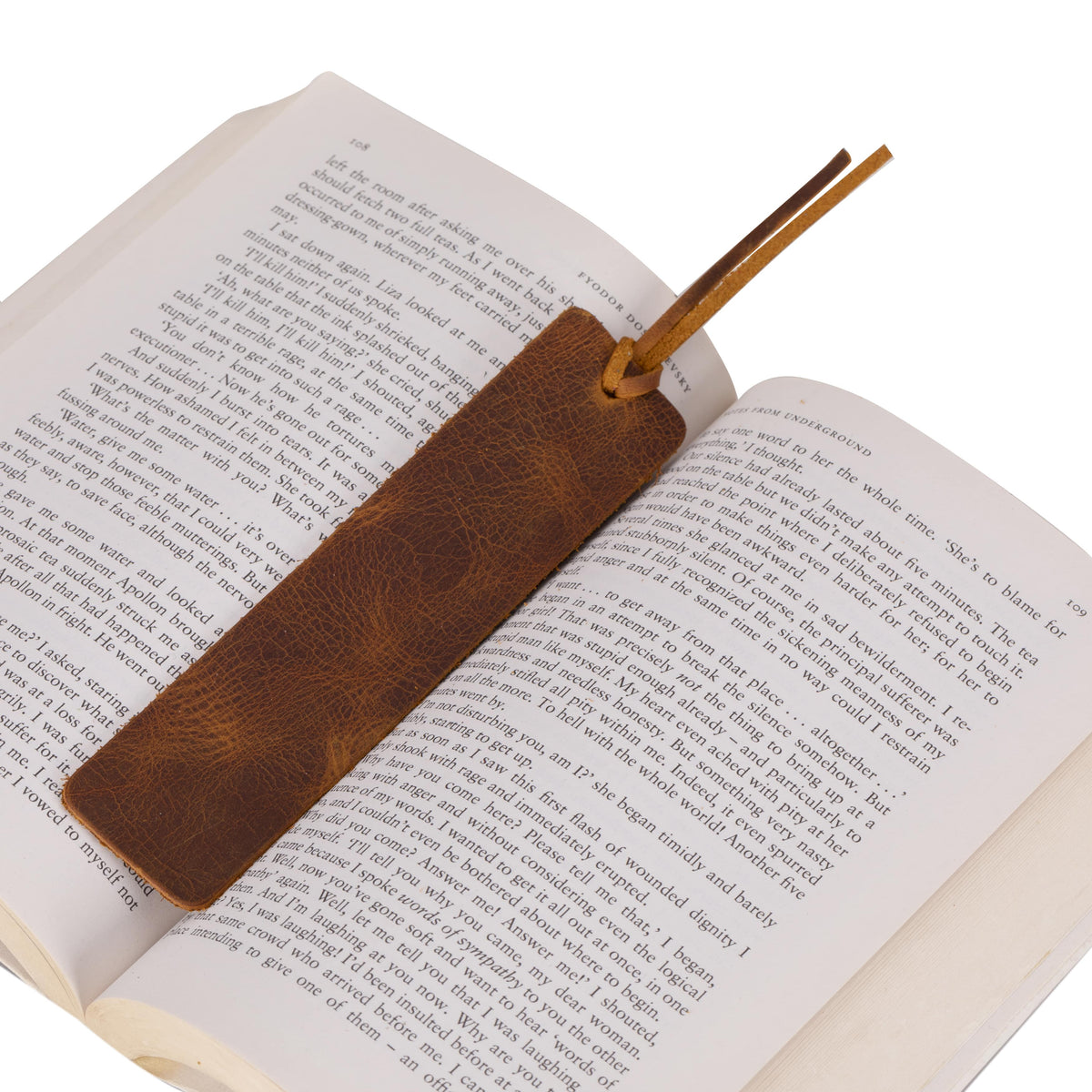 Brown leather bookmark on an open book with a white background