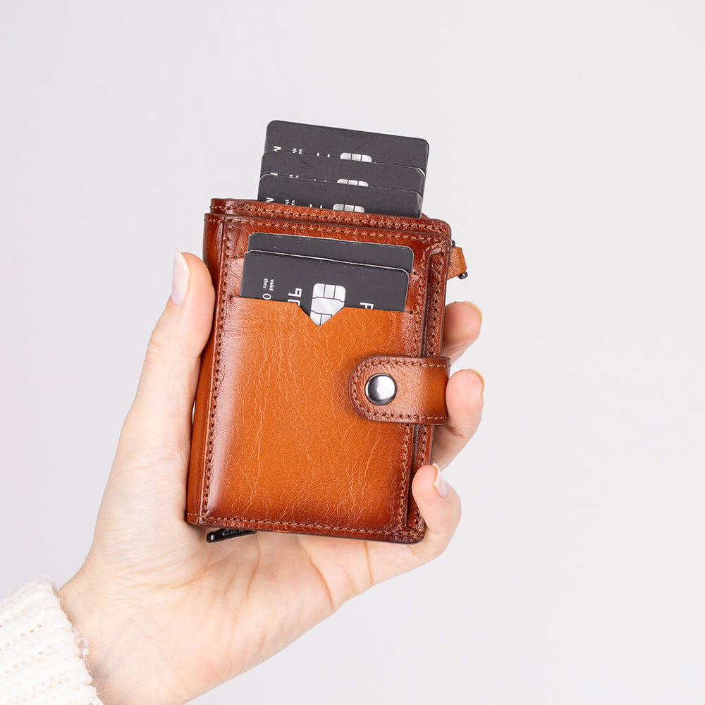 Brown leather wallet with cards held in a hand against a light gray background