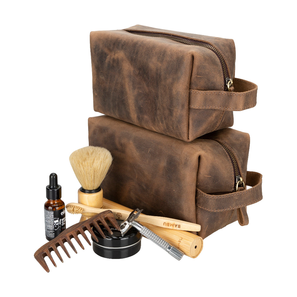 Brown leather toiletry bag with grooming tools on a white background
