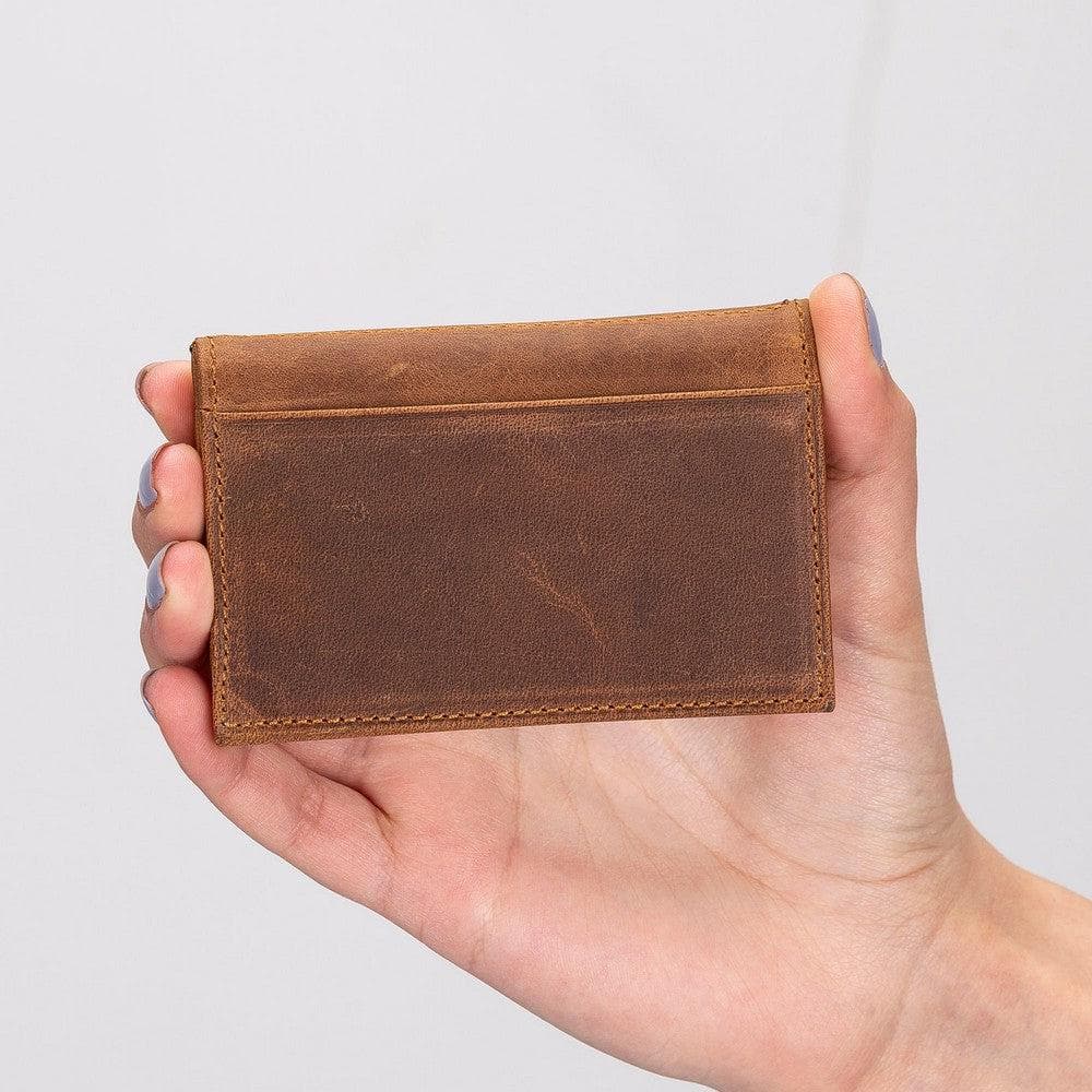Hand holding a brown leather wallet against a light gray background