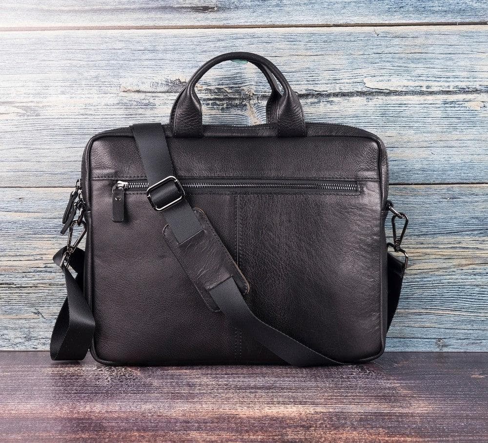 Black leather briefcase with shoulder strap on a wooden surface