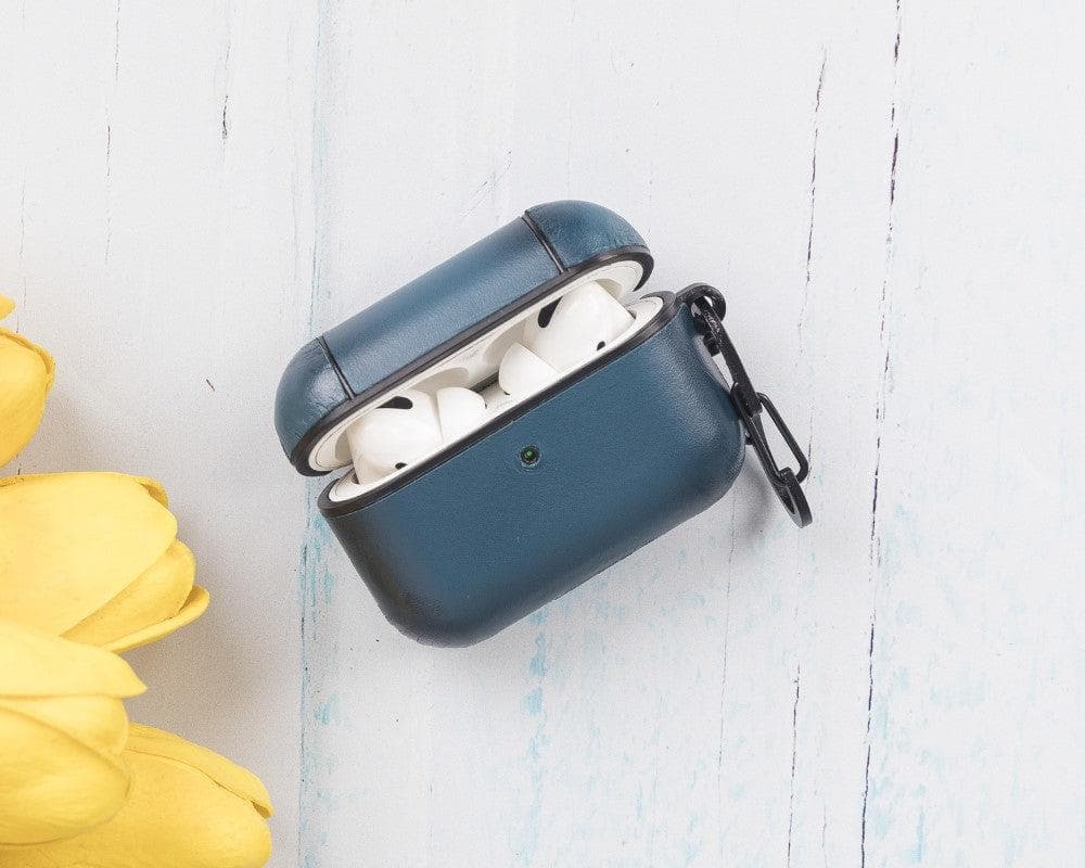 Blue wireless earbud case with white earbuds on a light wooden surface with yellow tulips.