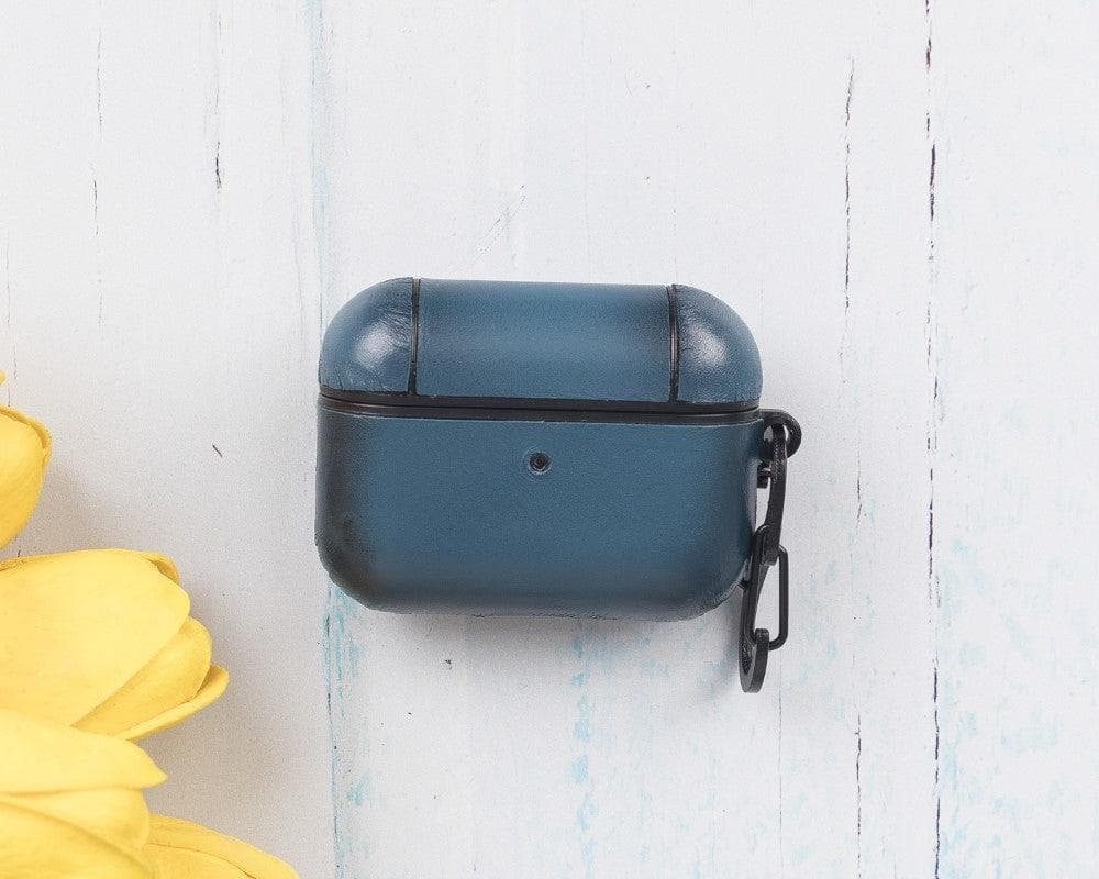 Blue earbud case with a keychain on a white wooden surface with yellow tulips.