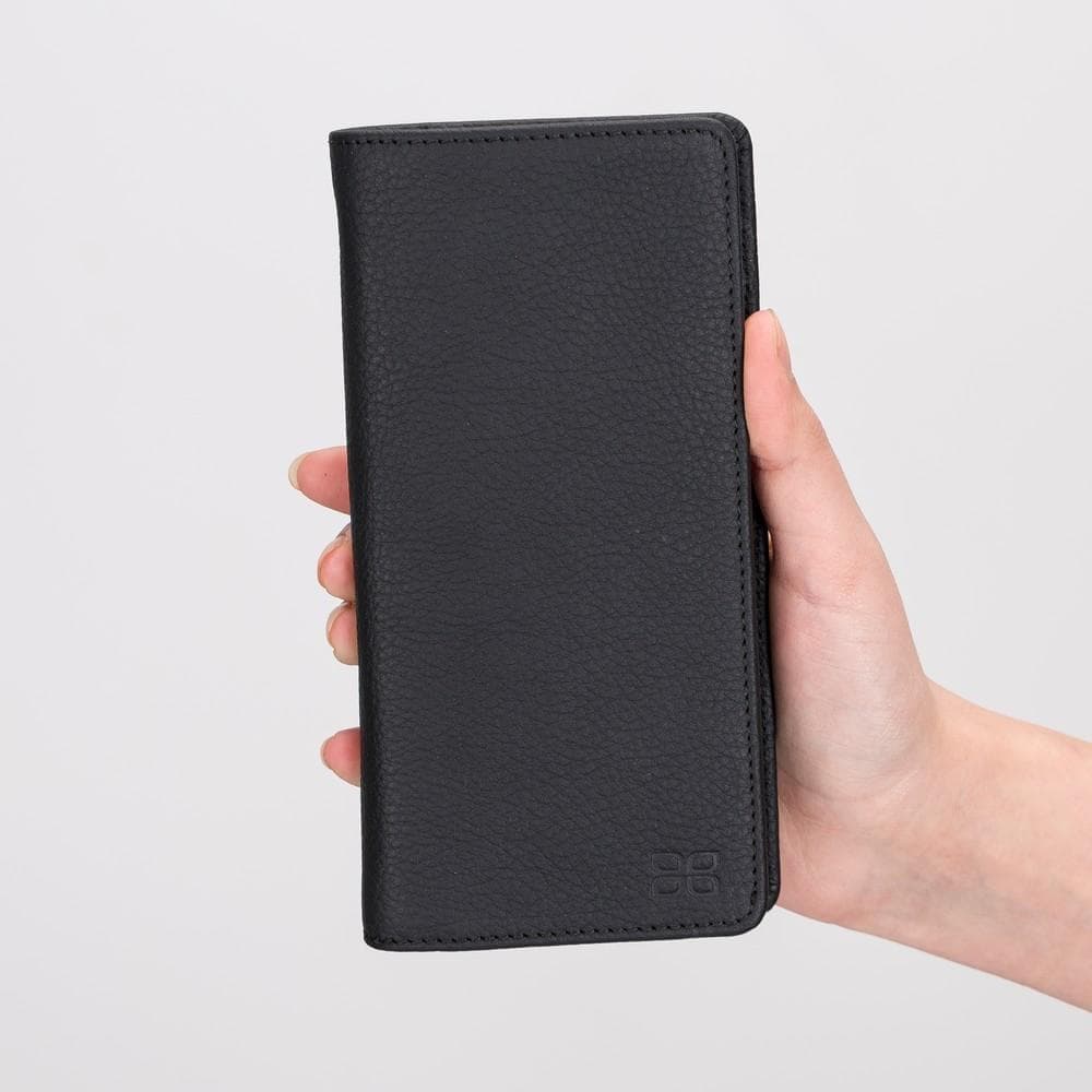 Black leather wallet held in a hand against a light gray background